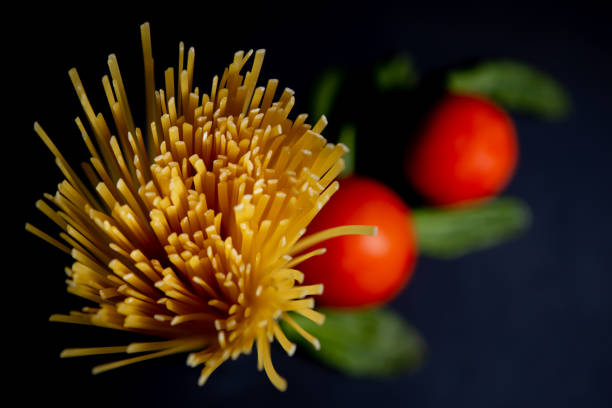 Spaghetti paste, tomato and other products for cooking on dark background top view. Space for text, top view.