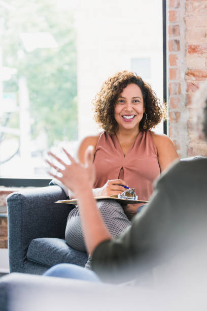 Attentive therapist listening to client An unrecognizable female therapy patient gestures while talking with a female therapist. The therapist attentively listens to the patient. mental health professional stock pictures, royalty-free photos & images