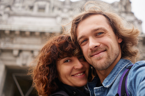 Positive smiling traveling couple making selfie on big city background, autumn colors and romantic mood. Travel, happiness and lifestyle concepts.