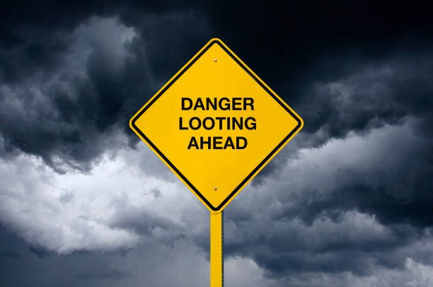 istock Danger Looting Ahead Road Sign in front of dark storm clouds 1257279833