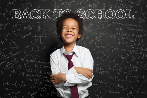 istock Funny black child on chalkboard background. Back to school concept 1257280899
