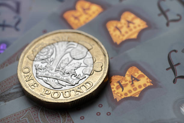 британский один фунт монеты место на вершине новых полимерных банкнот с видимым символом фунта и голограммы - one pound coin coin pound symbol falling стоковые фото и изображения