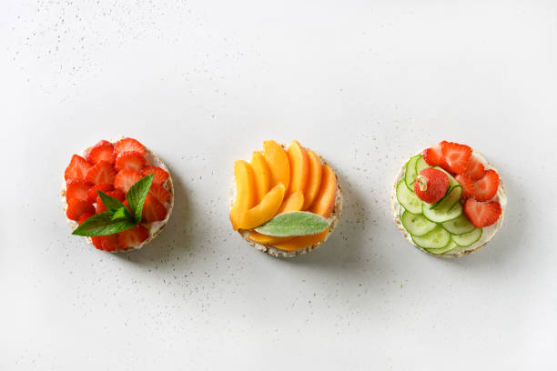 istock Puffed rice cakes with different toppings friuts and vegetables on white. Vegan snacks. 1257290373