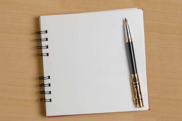 istock Top view of a blank notepad next to a pen on a wooden background. 1257290527