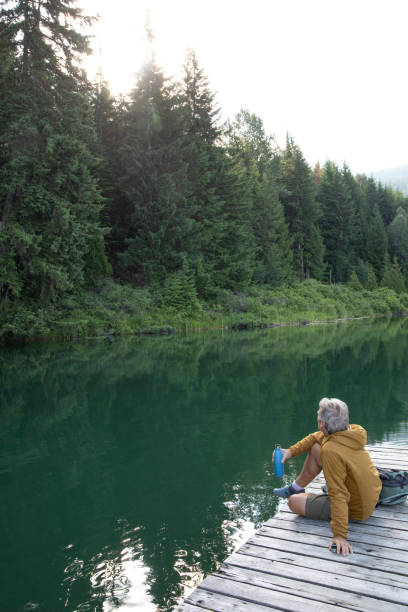 istock Hiker relaxes on lakeside pier and drinks from water bottle 1257292386