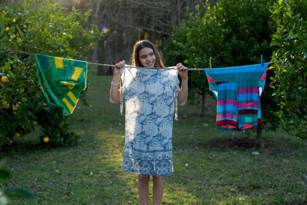 Child clothes and toy hanging and drying on drying rack on yellow background