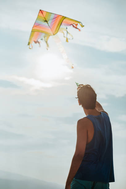 istock Teenage boy flying kite on beach 1257293919