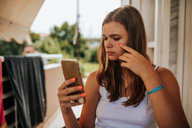 Skin problems Young girl looking at her front camera on mobile phone, and she's sad about her acne problem cheek cell stock pictures, royalty-free photos & images