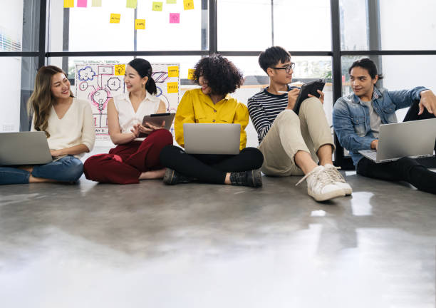istock Group of young happy Asian creative business people or hipster student using electronic devices tablet and laptop connection together in modern office. Creative lifestyle young people concept 1257294783