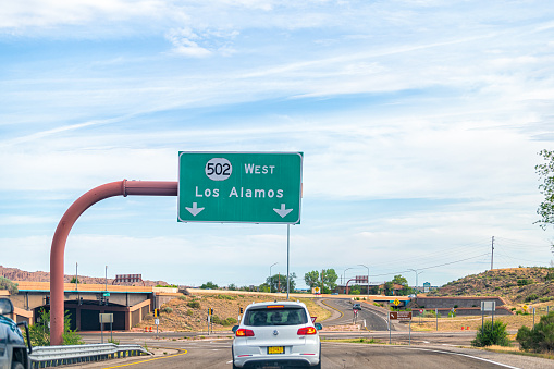 Santa Fe, USA - June 17, 2019: New Mexico desert with cars on road highway sign to Los Alamos driving with street 502 west