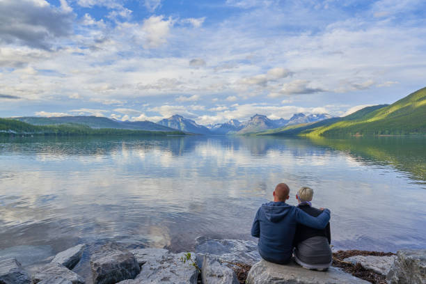 couple looking at the beautiful natural scenery of glacier national park's lake mcdonald area during the summer in montana, usa. - montana mountain mcdonald lake us glacier national park imagens e fotografias de stock
