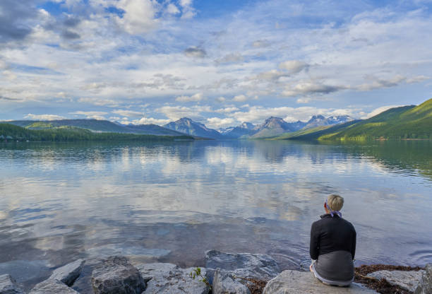 woman looking at the beautiful natural scenery of glacier national park's lake mcdonald area during the summer in montana, usa. - montana mountain mcdonald lake us glacier national park imagens e fotografias de stock