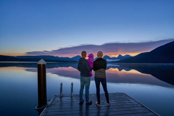 family take in a vibrant sunrise in the beautiful natural scenery of glacier national park's lake mcdonald area during the summer in montana, usa. - montana mountain mcdonald lake us glacier national park imagens e fotografias de stock