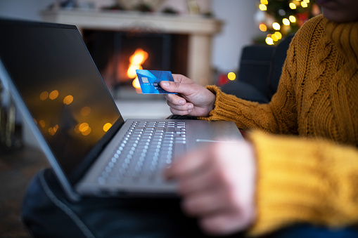 Young woman shopping for gifts Christmas , online shopping next to the fireplace