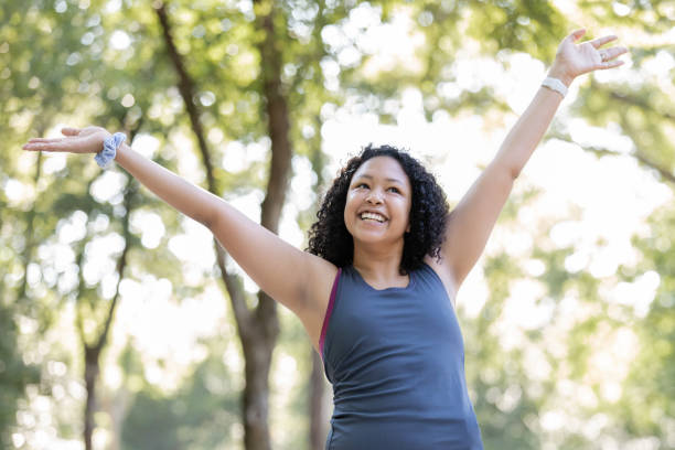 istock Woman lifts hands in celebration after running on running path 1257301457