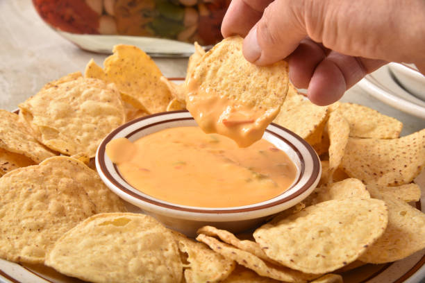 istock Dipping a corn chip into a hot cheese sauce 1257302355