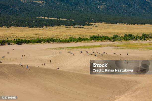 Groups Of Tourist Hikers Walk On Giant Desert Sand Dunes Surrounded By Mountains At The Great Sand Dunes National Park In Alamosa Colorado Usa Stock Photo - Download Image Now