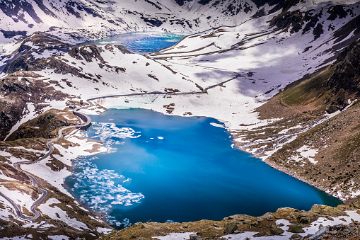 Mountain road and Lake Agnel and Serru at distance, snowcapped landscape – Gran Paradiso, Italy