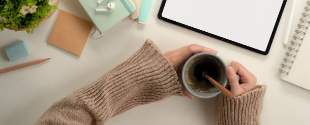 istock Female student hands holding coffee cup while sitting at worktable with mock up tablet and stationery 1257321605