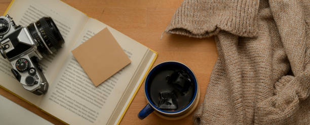 istock Study table with coffee cup, sweater, opened book, notepad and camera on wooden table 1257321633