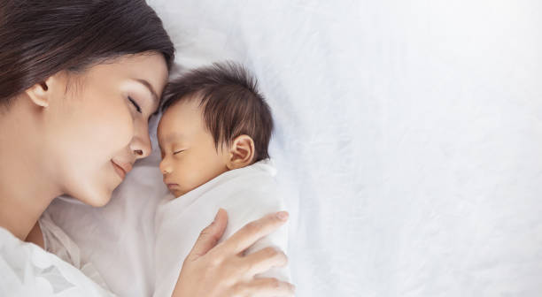 Close up portrait of beautiful young asian or caucasian mother girl kissing her healthy newborn baby sleep in bed with copy space. Healthcare and medical love asia woman lifestyle mother's day concept Close up portrait of beautiful young asian or caucasian mother girl kissing her healthy newborn baby sleep in bed with copy space. Healthcare and medical love asia woman lifestyle mother's day concept mother and baby stock pictures, royalty-free photos & images