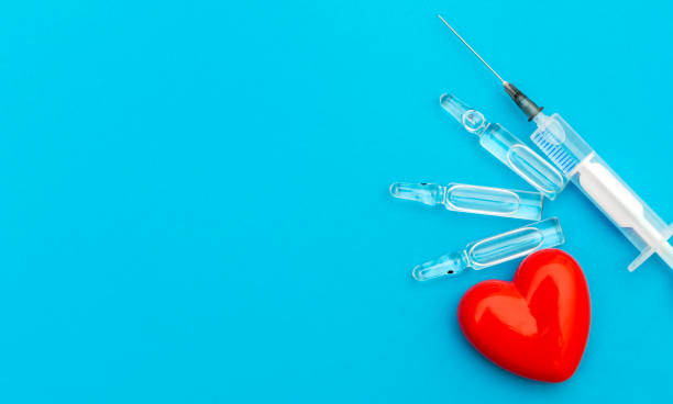 Syringe with ampoules and red heart on blue background. Medical concept. Syringe with ampoules and red heart on blue background. Medical concept. pericarditis stock pictures, royalty-free photos & images