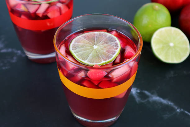 Closeup a Glass of Red Wine Sangria with Blurry Another Glass and Limes in Background