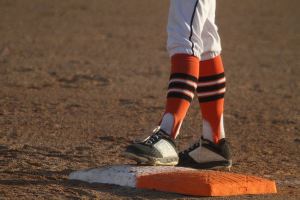 jugador de béisbol de pie en la primera base - orange uniform fotografías e imágenes de stock