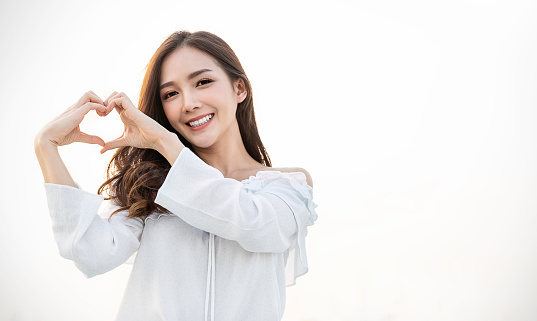 Portrait of young beautiful asian woman hands gesture in heart shape on city sky roof top. Smile face asian girl wear casual cloth. Japanese girl lifestyle, lovely woman valentinesâ day concept