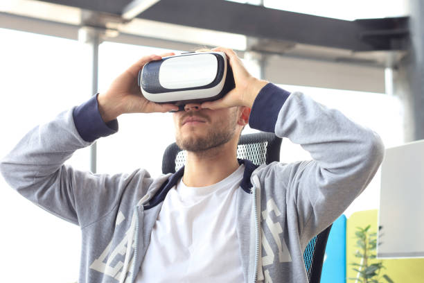 istock Young man playing game using virtual reality headset in the playing club. 1257336027