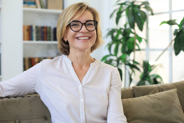istock Beautiful blond middle aged woman relaxing sitting on sofa. 1257337033