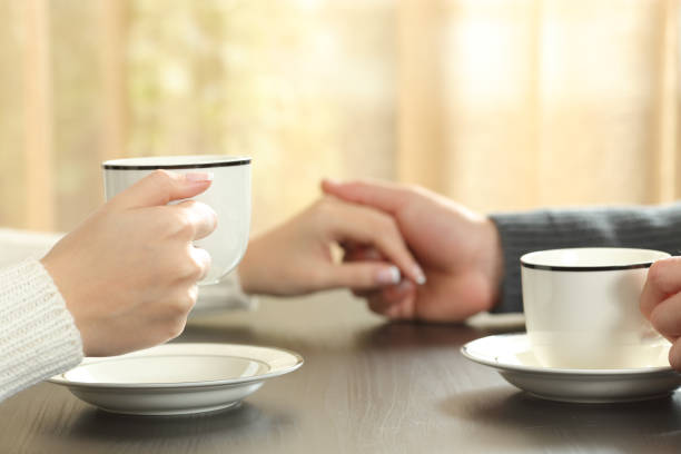 istock Couple holding hands with coffee cups on a table at home 1257340849