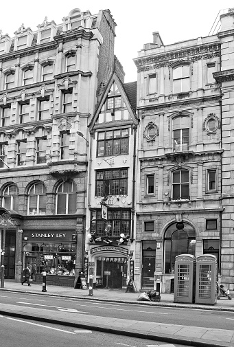 London, United Kingdom- August 24, 2012:  Black and white photo of Fleet Street with historical houses, tavern and few people