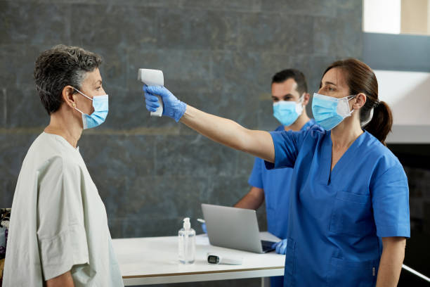 istock Nurse with Infrared Thermometer at Temperature Checkpoint 1257342922