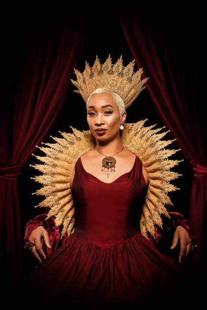 Beautiful mixed race historical african Queen character wearing a period dress in a studio shot