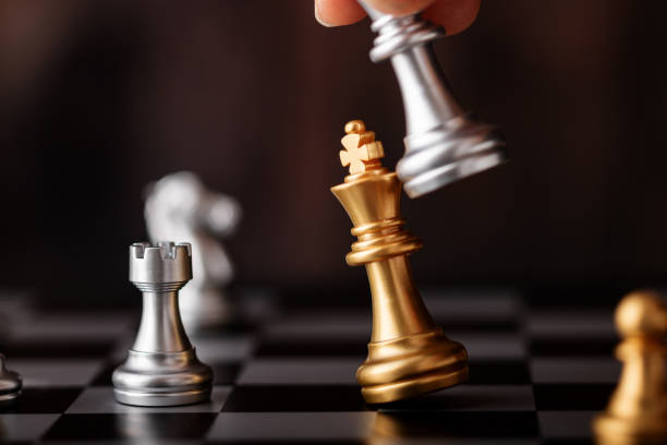 istock hand holding silver king attack gold leader in game 1257345533