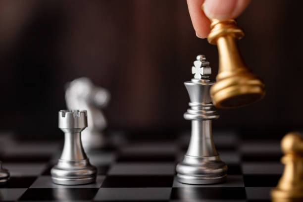 istock hand holding gold king attack silver leader in game 1257345843