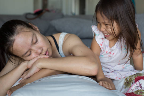 istock Tired mom sleeping on the couch next to her naughty daughter. 1257346741