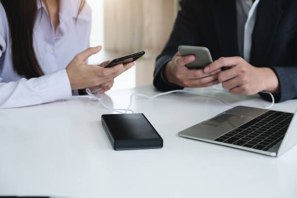 istock people using power bank charge to mobile phone. Tech Device Charge Sharing Concept. 1257347307