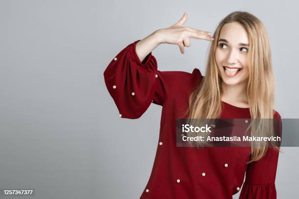 Im Fed Up With This Stylish European Girl With Long Blonde Hair Shoots In Temple Tilts Head Dressed In Casual T Shirt Demonstrates Suicide Gesture Isolated On Gray Background Stock Photo - Download Image Now