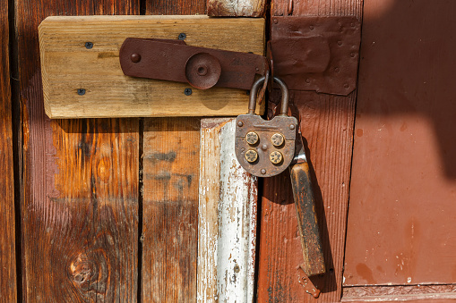 Vintage mechanical combination lock hanging on door. The door of the house is locked.