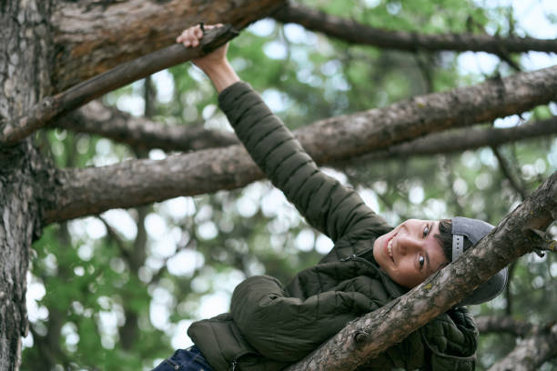 istock teenage boy poses on a tree, lying on a big branch and dreaming 1257352221