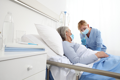 Nurse talking to a Latin American woman visiting a patient in the ICU at the hospital - healthcare and medicine concepts