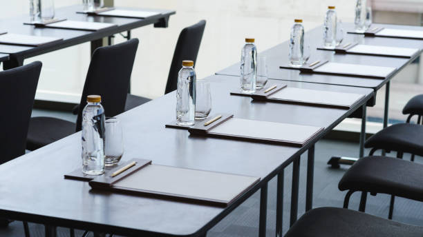 istock Plastic water bottles, Drinking glasses with pencil and white papers setup on the table prepared for seminar or business meeting in the hotel conference room 1257355630