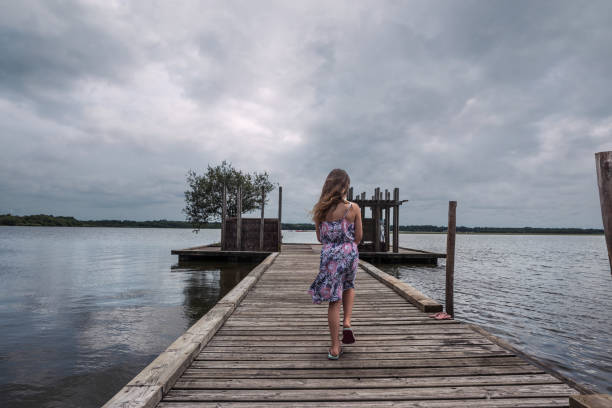 istock Pretty young girl strolling on a pontoon by a lake 1257356897