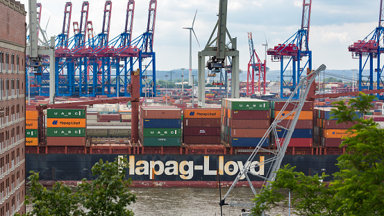 Hamburg, Germany - June 20, 2020: View on the middle part of a Hapag-Lloyd container ship on Elbe river. Harbour cranes in the background.