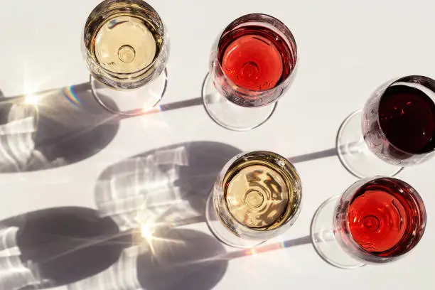 Red, rose and white wine top view in sunlight. Assorted wine in glass. Dark shadows