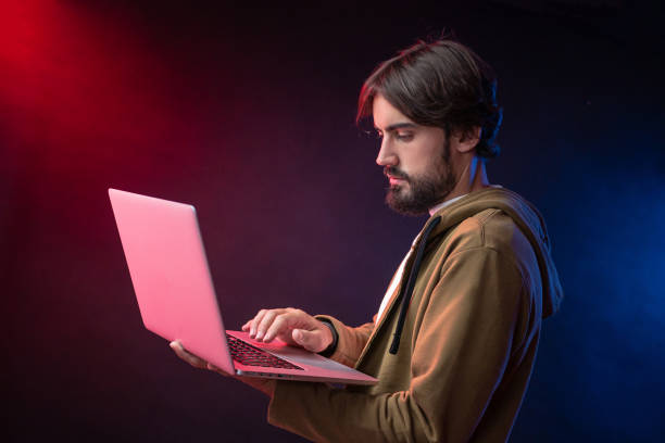istock bearded guy in hoodie with laptop in neon light 1257360835