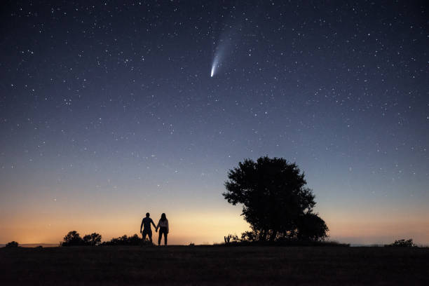 istock Young couple watching the Neowise comet under the bright night sky 1257361011