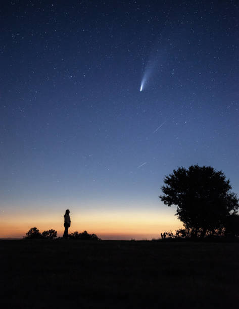 istock Young woman watching the Neowise comet under the bright night sky 1257362141